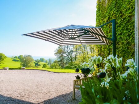 Shade Becomes the New Outdoor Luxury at RHS Chelsea Flower Show 2026 Luxury garden terrace with a large cantilever parasol creating shade over an outdoor dining area