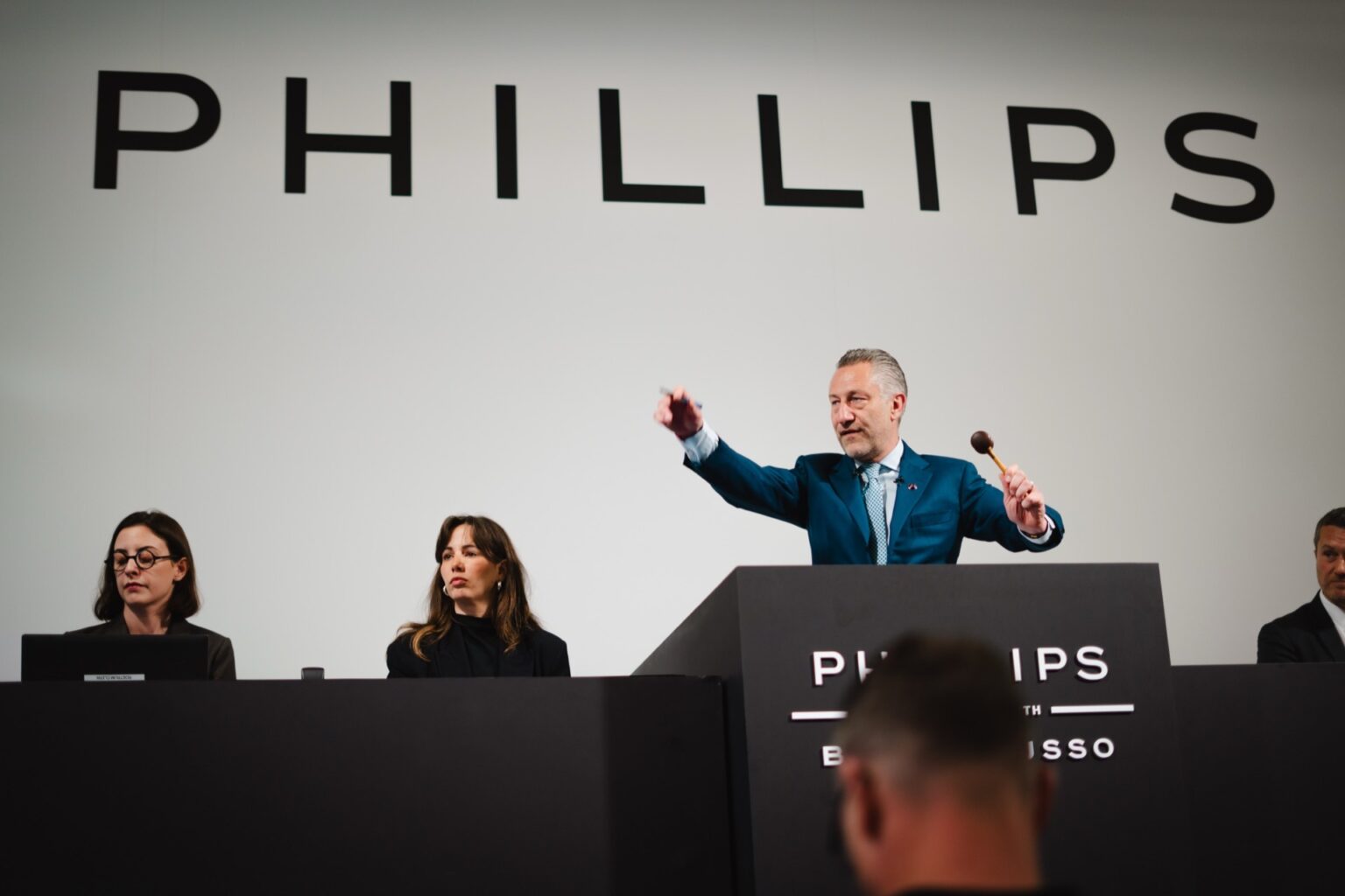 Auction room during a major Geneva watch sale with collectors bidding on rare Patek Philippe and independent watches