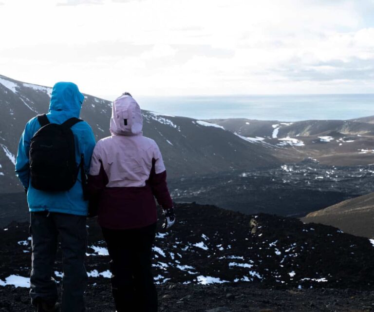 Why Iceland’s Best Hikes Are Better With a Local Guide Hikers crossing a rugged Icelandic highland trail with mountains and glacial river in the distance