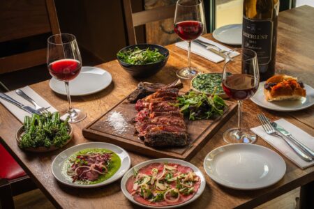 Vivat Bacchus Brings Club Carnivore Back to Farringdon This July A convivial red wine dinner table with grilled meat dishes and magnum bottles at Vivat Bacchus Farringdon