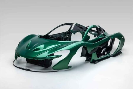 Metallic green McLaren P1 body panels with exposed carbon fibre accents in a shipping crate