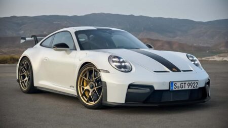 Porsche sports cars lined up outside a modern factory as the brand shifts focus to profitability