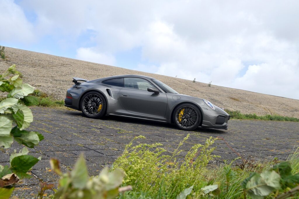 Porsche’s New 911 Turbo S Makes 711bhp Feel Remarkably Usable Porsche 911 Turbo S 992.2 driving on a road with wide rear arches and fixed rear wing visible