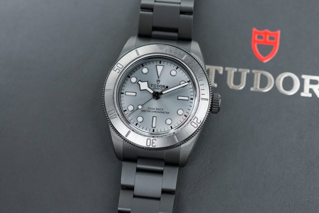 Five modern dive watches arranged on a dark wet surface with ceramic, titanium and steel cases