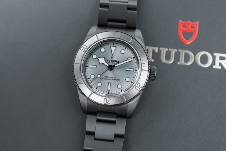 Five modern dive watches arranged on a dark wet surface with ceramic, titanium and steel cases