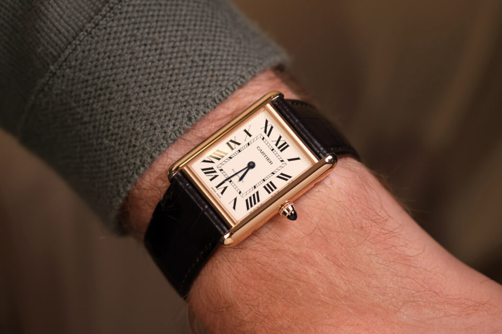A selection of rectangular dress watches with Art Deco styling arranged on a dark tabletop