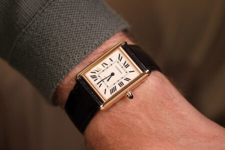 A selection of rectangular dress watches with Art Deco styling arranged on a dark tabletop