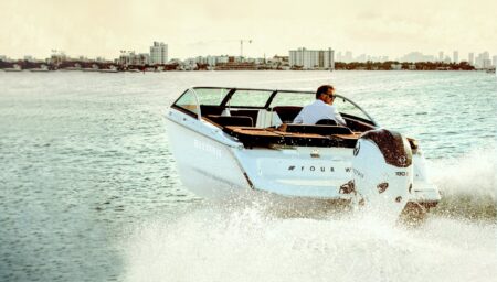 Electric luxury powerboat cruising quietly across calm water near a modern marina