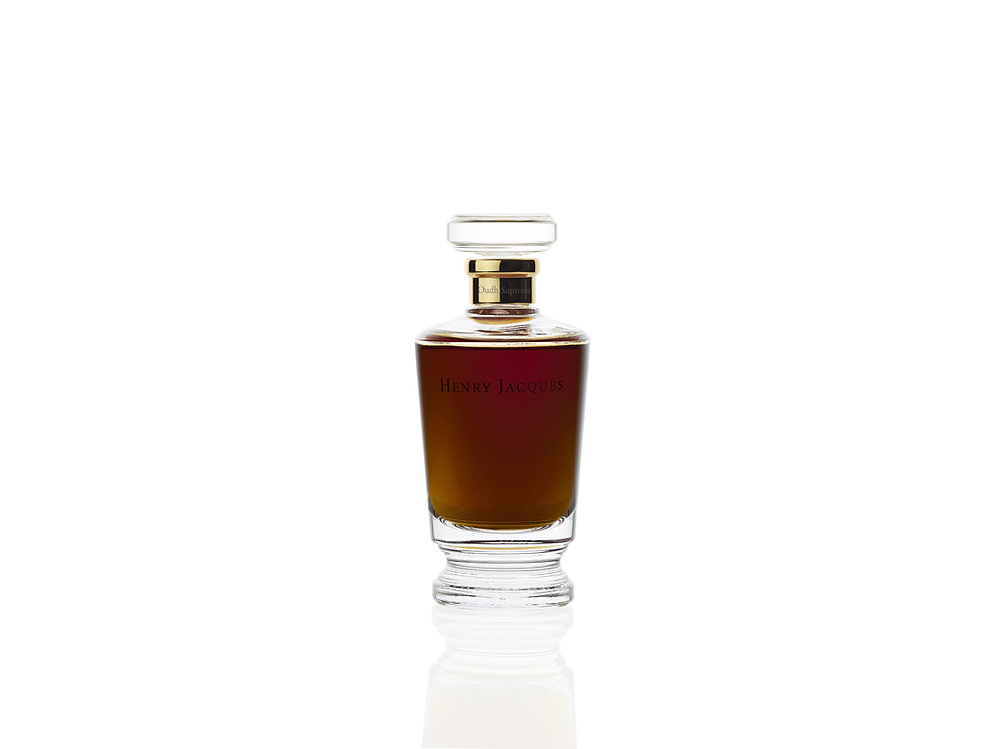 Henry Jacques Oudh Supreme fragrance bottle styled with warm oud wood and amber-toned light
