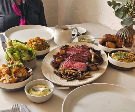 Cumbrian Pubs Where the Food Is Worth the Journey A traditional stone pub in Cumbria with diners inside and Lake District hills beyond