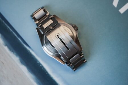 Close-up of a modern luxury watch clasp with a leather strap and metal bracelet nearby