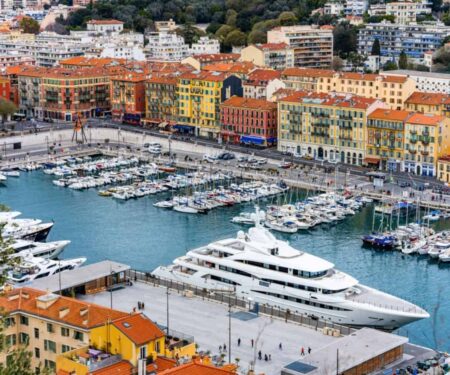 Where to Base a French Riviera Superyacht Charter Superyacht anchored off the French Riviera near a sunlit Mediterranean harbour