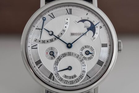 Close view of a luxury watch dial showing fired enamel texture and polished hands