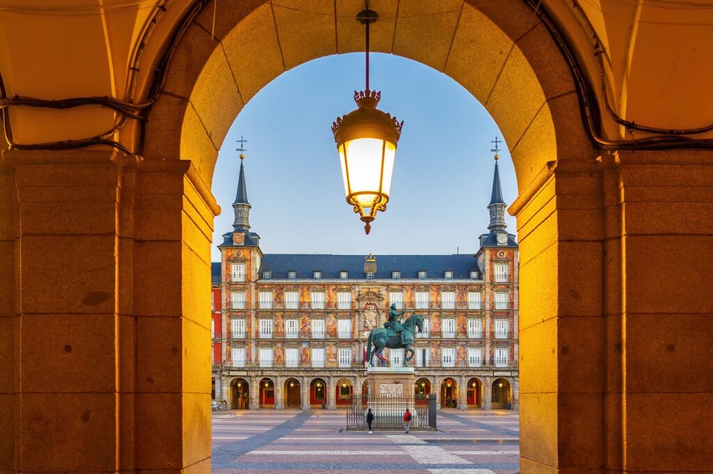 Madrid street scene near historic architecture with warm evening light and people walking through the city