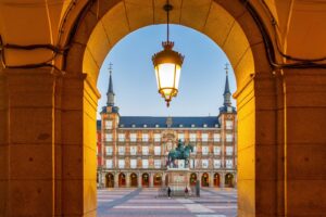 Madrid street scene near historic architecture with warm evening light and people walking through the city