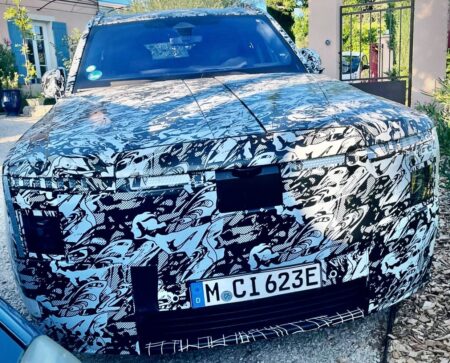 Camouflaged Rolls-Royce electric SUV prototype showing its front end and split bonnet