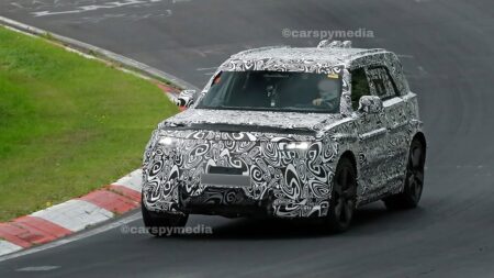 Camouflaged electric Land Rover Defender prototype testing with a rectangular tailgate box
