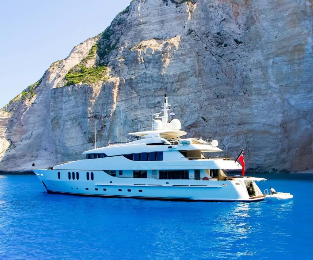 The Ionian Is Greece’s Smarter Superyacht Charter Alternative Superyacht anchored in clear turquoise water off a green Ionian island in Greece