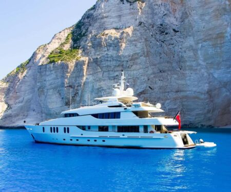 Superyacht anchored in clear turquoise water off a green Ionian island in Greece