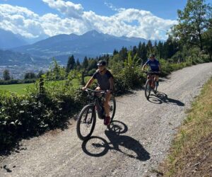 E-mountain bikes on a forest trail above Innsbruck with Alpine pastures and the Nordkette mountains nearby