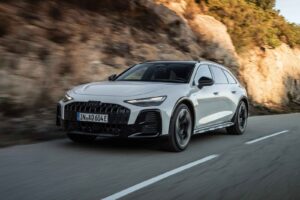 Audi A6 allroad driving on a road in a rugged luxury wagon setting